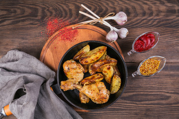 Fried chicken legs with fried potatoes in pan