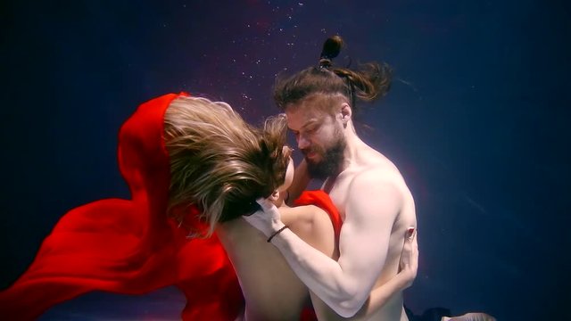 naked man and woman are hugging to each other tenderly during having sex underwater in pool