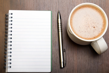 Blank notebook, pen and cup of coffee on wooden brown background, copy space.