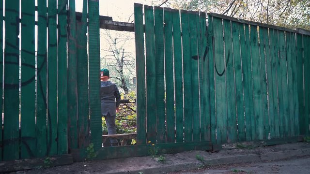 The boy runs through the gap in the old wooden fence