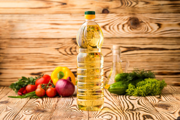 Bottle of sunflower oil on a wooden table with a composition of vegetables in the background