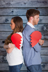 Side view of young couple holding broken heart against wooden background in blue