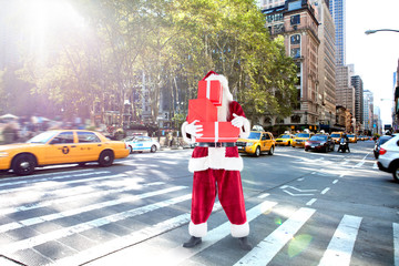 Santa covers his face with presents against new york street