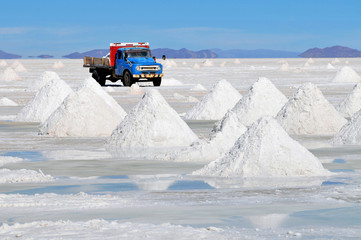 Piles of drying salt and reflection in the water at the Salar de Uyuni (salt flats) in Bolivia.