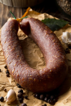 German specialty salami hard cured sausage whole with spices on wooden table