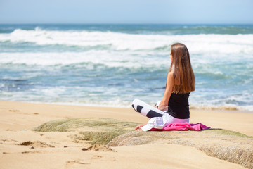 Fototapeta na wymiar Smiling active young woman doing yoga on the beach