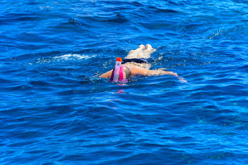 Tourists swim in the transparent turquoise sea and see beautiful colorful fish on the background of corals in the Red Sea. Relaxation during rest. Egypt.