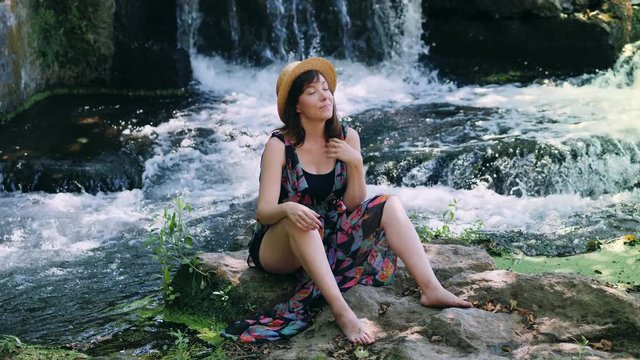 Nature,waterfall, summer:pretty woman relaxing near waterfall