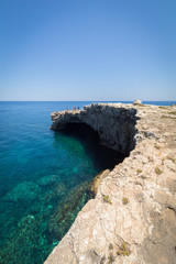 Rocky Sea caves and natural limestone arches over beautiful crystal clear azure turquoise blue waters of the Mediterranean on the small holiday island of Comino, Malta, June 2017