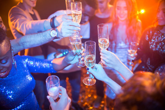 High Angle View At Multi-ethnic Group Of Laughing Young People Enjoying Dance Party In Nightclub And Drinking Champagne, Focus On Clinking Glasses