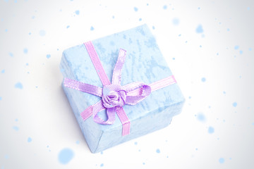 Snow falling against overhead of blue gift box with purple ribbon
