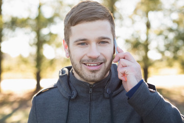 Smiling man using mobile phone in the forest