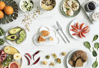 The top viev of super food on the white marble table. Flat lay. Variuos vegetables ingredients and healthy food for vegetarians. Breakfast table.