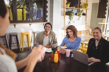 Young friends looking at waitress while sitting at table