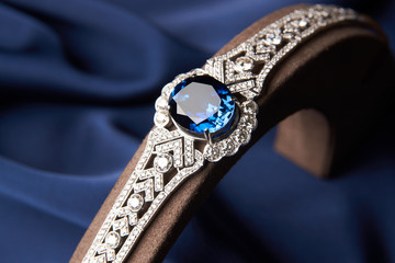 Close-up of a Beautiful platinum bracelet. Luxury women bracelet with diamonds and sapphire on blue silk background, close-up