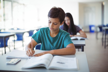 Obraz na płótnie Canvas Schoolboy doing homework in classroom
