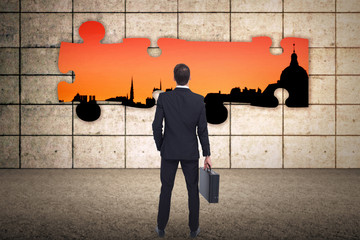 Rear view of businessman holding a briefcase against cityscape stencil on red sky