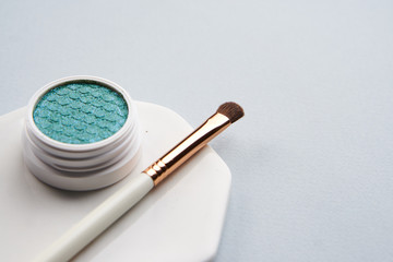 makeup brush and green shadows on gray background