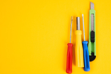 office knife and screwdrivers on a yellow background