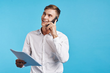 young man in shirt talking on the phone on blue background