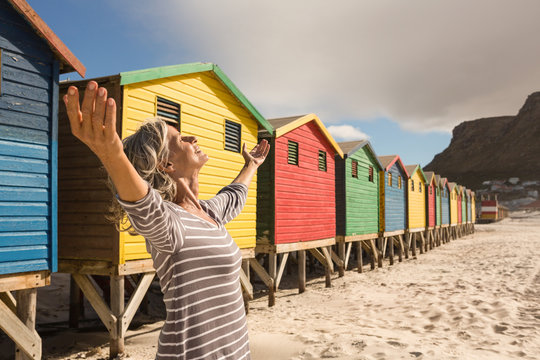Woman with arms raised standing on sand - Powered by Adobe