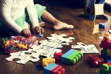 African descent kid enjoying puzzles on wooden floor