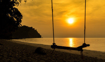 empty silhouette beach swing on sunrise and golden sky time