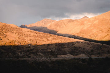 A highway running through the mountains in Colorado during sunset. 