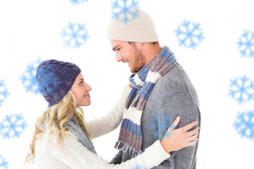 Attractive couple in winter fashion hugging against snowflakes