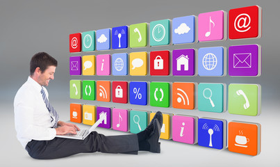 Businessman using laptop and smiling against grey vignette