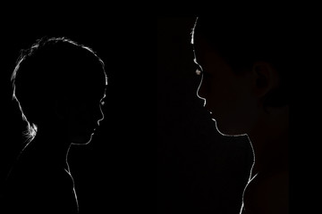 Two silhouettes of the boy's face on a black background. Studio photography
