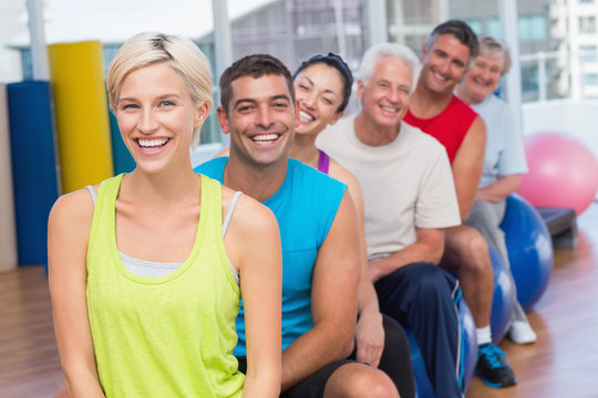 People relaxing on exercise balls in gym class - Powered by Adobe