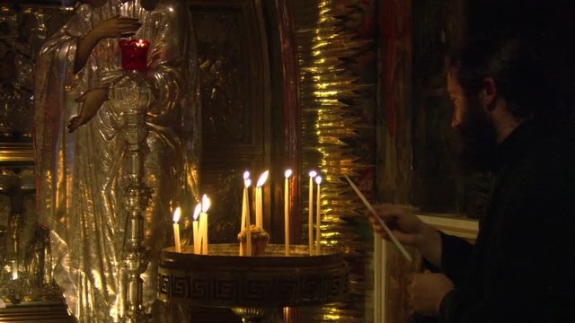 Monk lighting candles in Church of the Holy Sepulcher, Jerusalem