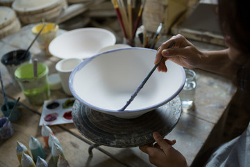 Female potter painting bowl