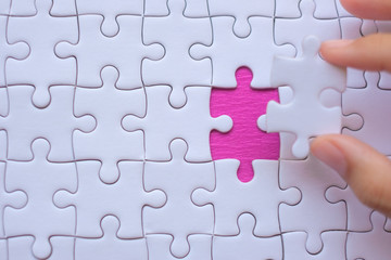 Fototapeta premium Woman Hand holding white jigsaw puzzle piece. Business solutions, target, success, goals and strategy concepts