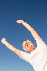 Low angle view of senior man exercising against blue sky