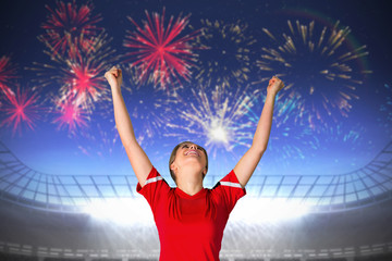 Fototapeta na wymiar Cheering football fan in red against fireworks exploding over football stadium