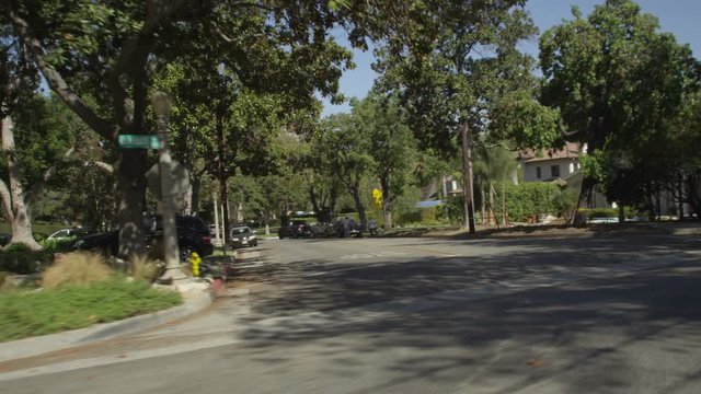 Left Front Three Quarter view of a Driving Plate: Car turns left from South Oak Knoll Avenue in Pasadena, California, and travels through affluent neighborhood on Old Mill Road, passing over speed bumps.