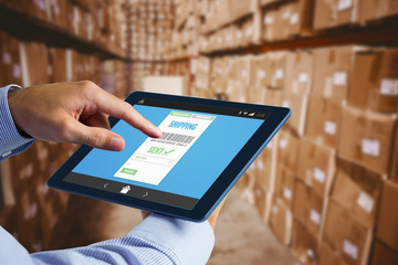 Man using tablet pc  against boxes in warehouse 