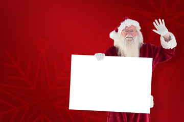 Santa holds a sign and is waving against red background