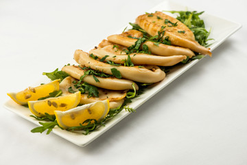 body of squid fried with lemon on white plate on white background