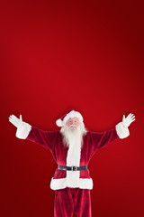 Jolly Santa opens his arms to camera against red background