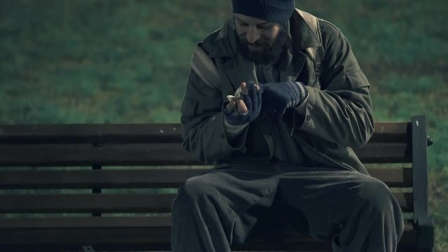 checking alms money, beggar on the bech counting his money