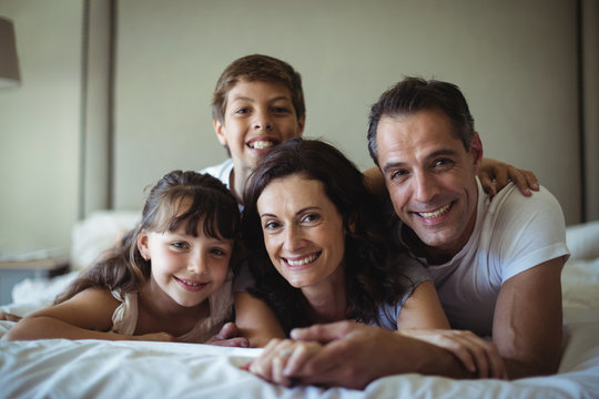 Portrait of happy family lying on bed in bedroom