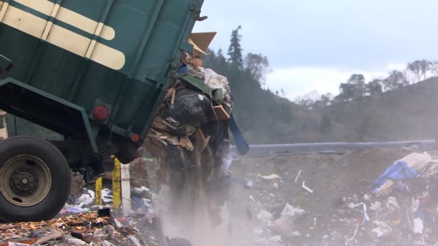 Trash pouring out of garbage truck into landfill
