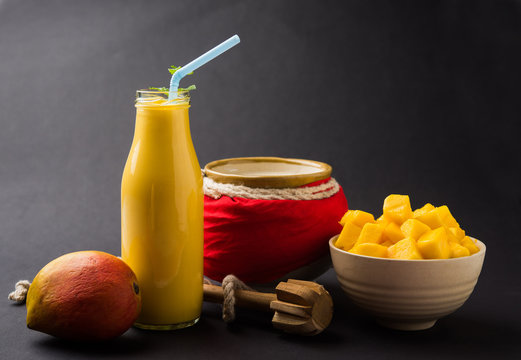 Mango Lassi Or Smoothie In Big Glass Or Small Bottles With Curd, Cut Fruit Pieces And Blender. Moody Background, Selective Focus
