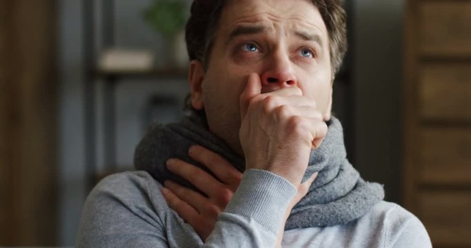Young ill caucasian man in the warm scarf caughing hard as he having a cold or influenza. virus Coronavirus   covid-19   flu  healthcare   illness immune infection  isolation  pandemic   self care  