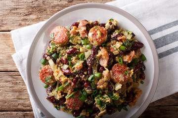 Brazilian food: Feijao Tropeiro with beans, sausage and bacon close-up on a plate. Horizontal top view © FomaA