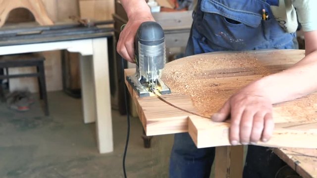 woodworker saws a round tabletop with a jig saw. joiner. carpenter