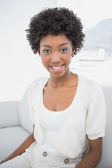 Smiling pretty brunette sitting on cosy sofa